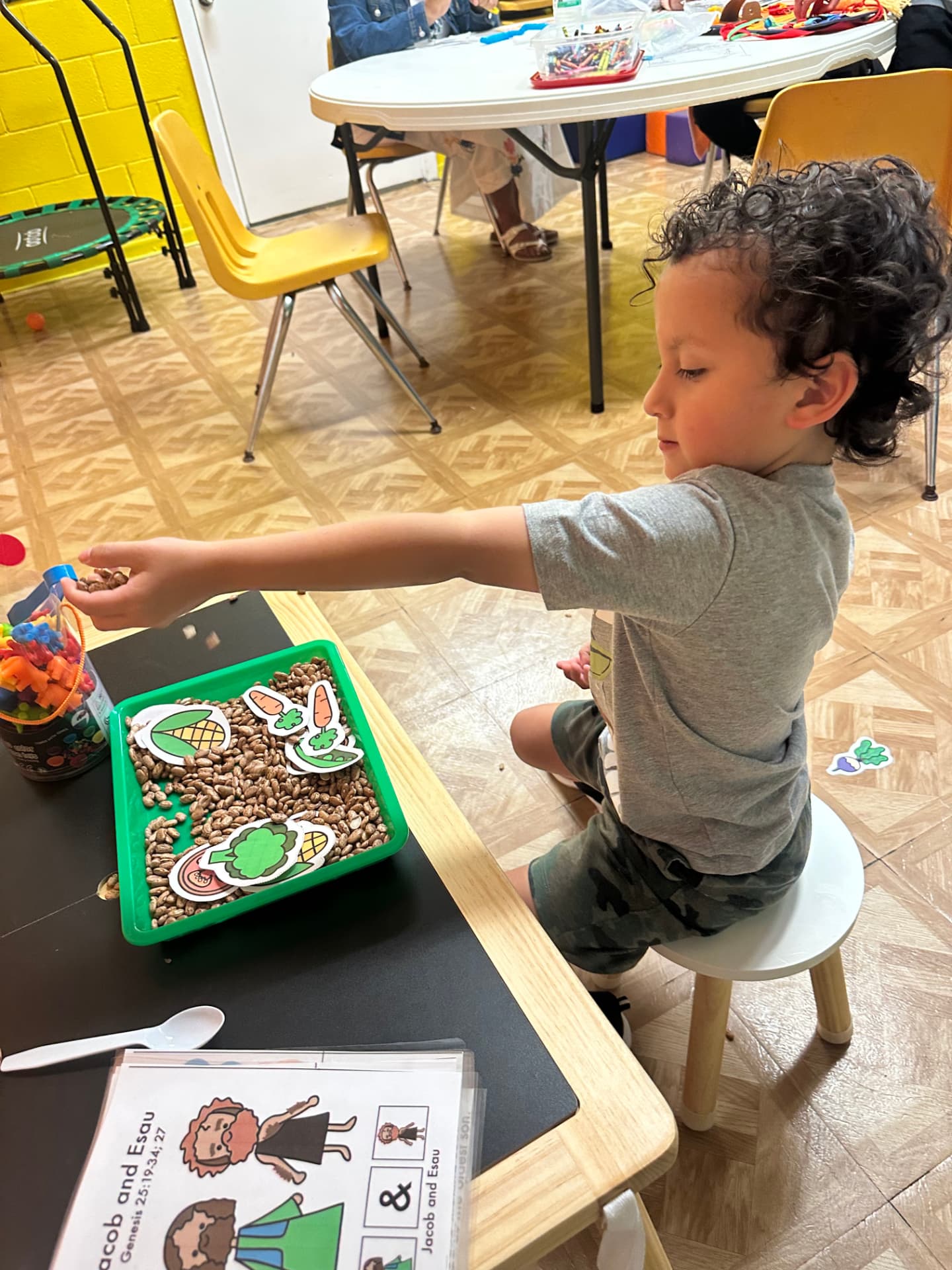 A child in The Ark Room sorting picture cards in a sensory bean bin